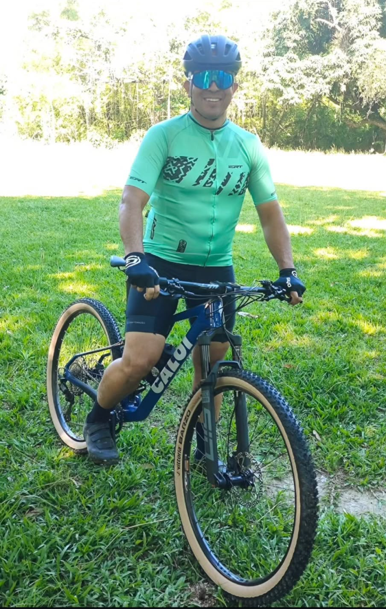 Aluno pedalando de bicicleta, com capacete e equipamento de ciclismo